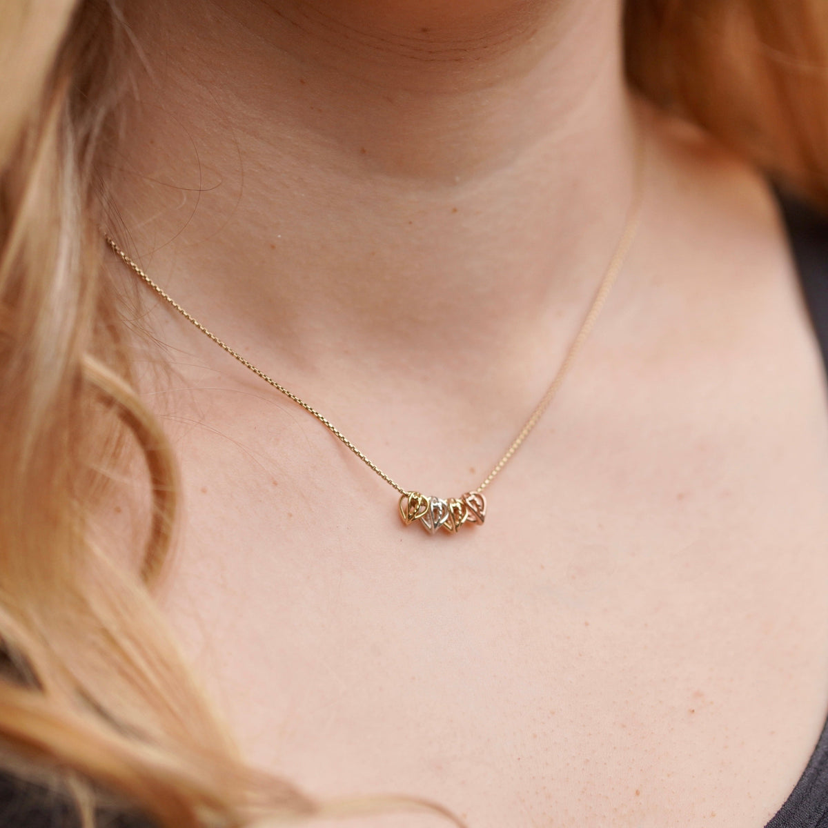 Close-up of a gold necklace worn by a person with blonde hair.