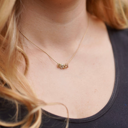 Close-up of a gold necklace worn by a person with blonde hair.
