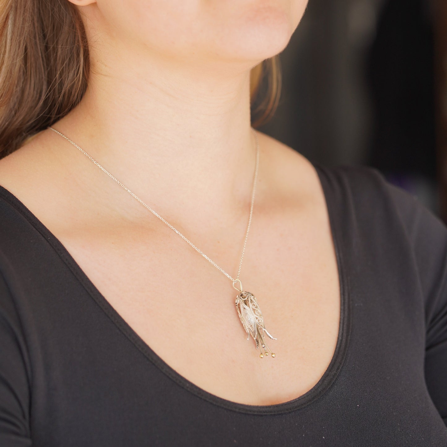Woman wearing a necklace with a pendant, close-up of the neck and chest area.