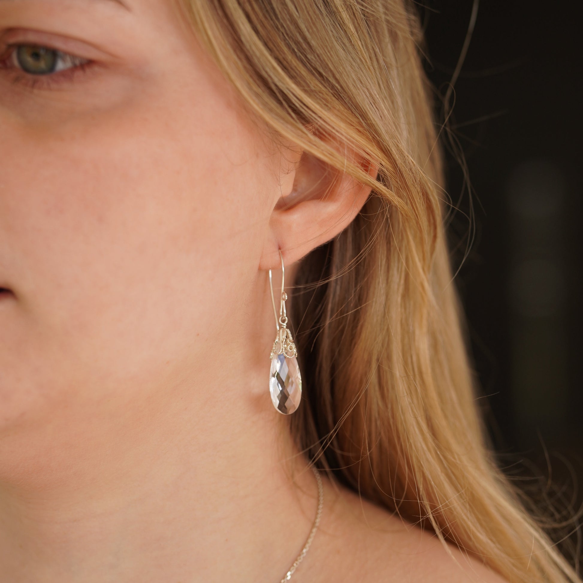 Close-up of a person wearing a silver earring with a blurred background