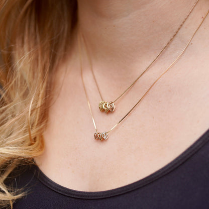 Close-up of a person wearing two gold necklaces with small pendants.
